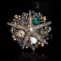 Detailed shot of vintage starfish brooch with rhinestones and emerald green gemstone. - Gray