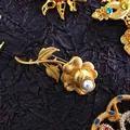 Detailed close-up of a luxurious vintage gold rose brooch with a white pearl center. - Baroque Rose (01)