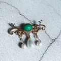 Close-up detail of a vintage baroque brooch featuring a green center and pearl pendants. - Green Oval Pearl Pendant Style (7)