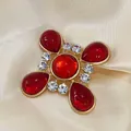 Gros plan d'une broche croix vintage en verre rouge avec métal doré et cristaux - Style Rouge (Style 1)