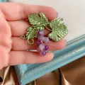 Detailed view of a vintage Baroque grape brooch with green leaves and purple beads - Purple Grape Style / Purple
