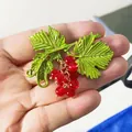 Detailed view of a vintage baroque grape brooch with green leaves and red berries. - Red Grape Style / Red