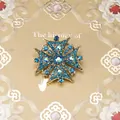 Macrodetail van een barokke vintage gouden kruisbroche met blauwe strassteentjes - Stijl 15 (Gradiënt Midden Strass Maltezer Kruis)