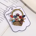 Close-up of a vintage flower basket brooch featuring colorful rhinestones on a card. - Multicolor Gem Flower Basket Style