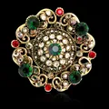 Vintage Baroque palace style brooch with green and red rhinestones on black background - Gold