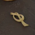 Detailed view of a vintage golden knot brooch with textured metallic finish on a stone - Matte Gold Twisted Knot Ribbon Style