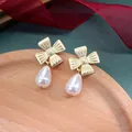 Detail van vintage gouden kruis oorbellen met elegante witte parel druppelhangers - Goud Strik Kruis Waterdruppel Parel Stijl (Stijl 20)