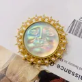 Gedetailleerde vintage zonnebroche met goudkleurige parellijst en iriserend midden - Iriserend Gezicht Zon (Stijl 7)