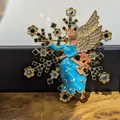 Gedetailleerde macro-opname van een vintage gouden engelbroche met blauw emaille - Sneeuwvlok Blauwe Engel