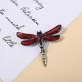 Close-up of a vintage red abalone shell dragonfly brooch on a cream background - Red Texture Style