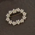 Close-up view of a vintage gold brooch featuring white pearls and sparkling crystal accents - Oval Pearl Flower Cluster Wreath Style