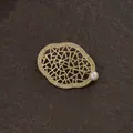 Detailopname van een vintage gouden barokke broche met geometrische patronen en parel - Barokke holle geometrische stijl