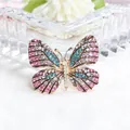 Elegante vlinderbroche in goud met sprankelende roze en blauwe kristallen steentjes. - Vlinder Stijl 16