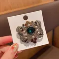Vista de cerca de un broche de lazo vintage de lujo con cristal verde y perlas finas. - Broche de Lazo / Verde