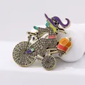 Detailed close-up of a vintage witch on bicycle brooch with enamel and crystals - Gray