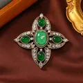 Nahaufnahme einer goldenen Vintage Kreuzbrosche mit grünen Steinen und Strass - Grün
