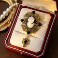 Close-up view of a vintage palace style cameo brooch with intricate gold-toned metalwork. - Lady Portrait Cameo (White) / White