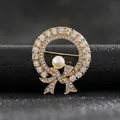 Macro view of elegant gold-toned wreath brooch with bow and central pearl detail. - Golden Bowknot Pearl Ring Style
