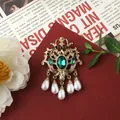 Detailed view of vintage Baroque brooch with green emerald gemstones and pearl tassels - Emerald Pearl