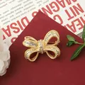 Close-up of a vintage golden bow-knot brooch with sparkling rhinestones. - Gold Bowknot