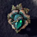Luxurious vintage flower brooch featuring green crystals and a large emerald centerpiece - Green