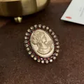 Nahaufnahme einer Vintage-Brosche im Barockstil mit roten und goldenen Strasssteinen - Retro-Porträt-Relief