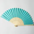 Detail view of a turquoise silk folding fan with an intricately carved bamboo frame. - Lake Green (No.4)