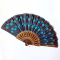 Detailed view of a sequined folding fan with a blue peacock feather embroidery pattern. - 23CM*42CM / Black Ribs Lake Blue Sequin
