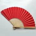 Detailed macro view of a 9-inch vibrant red folding fan featuring natural bamboo ribs - Red