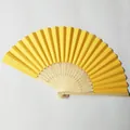 Detailed view of a bright yellow blank paper folding fan with wooden ribs - Earthy Yellow