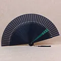 Vue détaillée d'un éventail pliant traditionnel noir de 21 cm avec pompon en soie. - Côte Noire Épissée Verte