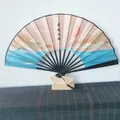 Detailed shot of a traditional Chinese folding fan with mountain sunrise landscape print - Black Rib Landscape Pattern / Black
