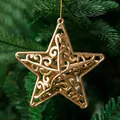 Close-up of a gold hollow star ornament with intricate swirl patterns on a green tree - 8cm 4 Pieces/Pack / Antique Bronze
