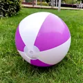 Close-up of a 36cm purple and white striped inflatable beach ball on green grass. - Purple White