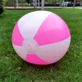 Detailed view of an inflated pink and white striped beach ball on green grass - Pink White