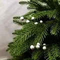 Detailaufnahme von silbernen Weihnachtsbeeren und grünen künstlichen Tannennadeln für DIY. - Silber