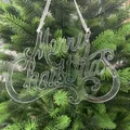 Nahaufnahme einer klaren "Merry Christmas" Dekoration an einem grünen Tannenbaumzweig - Transparenter Frohe Weihnachten Haken / 15cm (1 Stück/Packung)