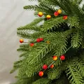 Gros plan d'une branche de baies de Noël artificielle avec des aiguilles de pin réalistes - Jaune Rouge