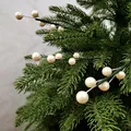 Nahaufnahme von dekorativen Weihnachtszweigen mit cremefarbenen Perlenbeeren auf Tanne - Weiß