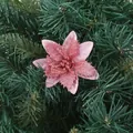 Detailed close-up of a pink glittery artificial Christmas flower on green pine branches - Pink