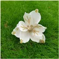 Detailed view of white artificial magnolia flower with gold glitter accents for Christmas. - White