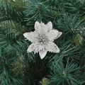 Detailed view of a silver glittery artificial poinsettia flower on a Christmas tree. - Silver