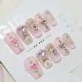 Détail de faux ongles roses faits main avec des gemmes en cœur et des nœuds dorés. - XS / Taozhi (CD020)