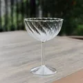 Elegant spiral ribbed clear glass champagne coupe set on a rustic wooden table - Ribbed Wavy Rim Style (bz2046) / Clear