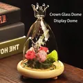 Detail of a crown-topped glass dome with preserved roses on a wooden base tray - Crown