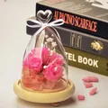 Elegant heart-shaped glass dome with pink preserved roses on a light wooden base - Heart