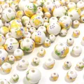 Vista dettagliata di perline in ceramica con fiori dipinti a mano, ideali per bracciali e gioielli fai da te. - Flora Gialla