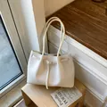 Minimalistische cremeweiße geflochtene Tasche mit Schnallendetail auf Holzhocker - Standardausführung / Weiß
