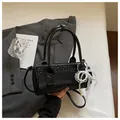 Close-up detail of a chic black cylindrical handbag with pearl and lace bow charm decor - Black (With Pearl Lace Pendant) / Black