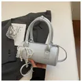 Close-up view of light blue barrel handbag featuring pearl and lace ribbon charm - Blue (With Pearl Lace Pendant) / Blue